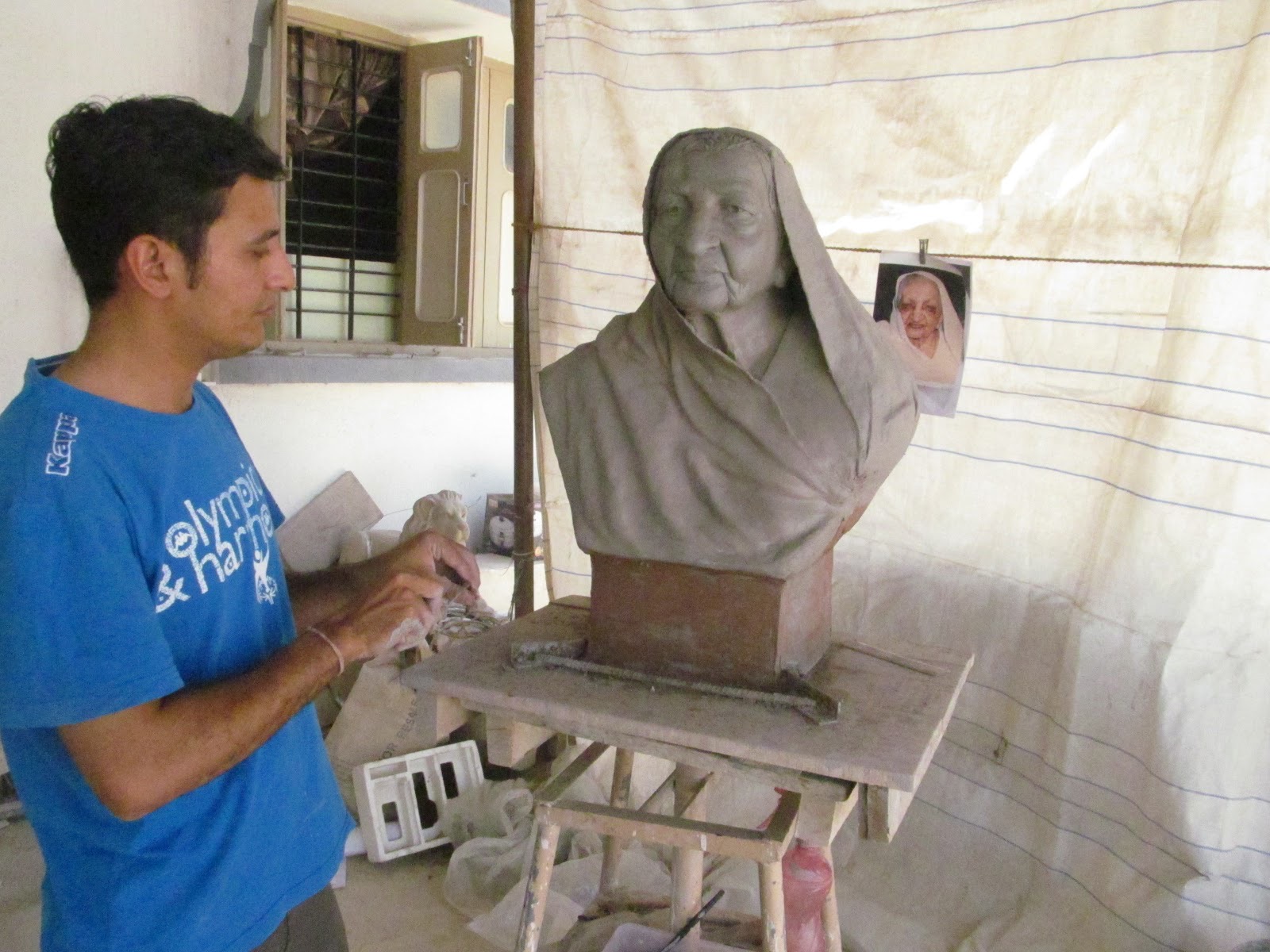 Sculptor modelling a clay portrait bust of an elderly woman from a photograph