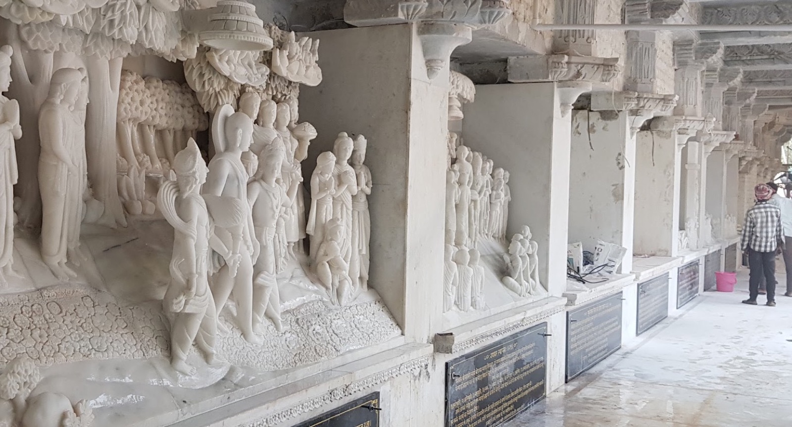 Row of white carved relief murals set along a temple corridor wall