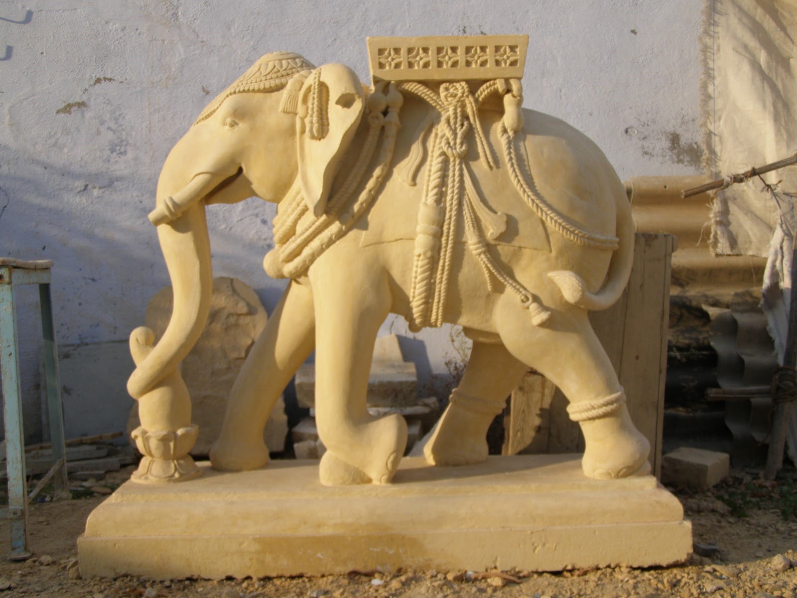 Sandstone elephant sculpture with carved ropes, tassels and saddle cloth
